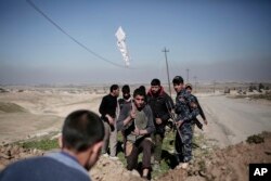 A civilian plants a white flag in the berm as he arrives at the defense line of Iraqi federal police forces in the town of Abu Saif after escaping Islamic State territory, Feb. 21, 2017.