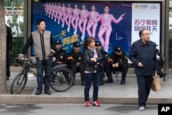 Residents wait near security personnel resting near a billboard featuring a popular actor in Beijing, China, Oct. 21, 2017. Instead of selfish, rich stars, the state is promoting performers who are all about patriotism, purity and other values that support the party legitimacy.