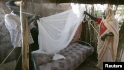 FILE - A Sudanese women gets help setting up a bed net. 