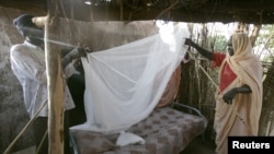 A Sudanese women gets help setting up a bed net (file photo)