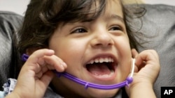 FILE - Three-year-old Amina of Iraq laughs during a hearing test. The WHO reports 360 million people around the globe suffer from disabling hearing loss and that nearly 32 million are children.