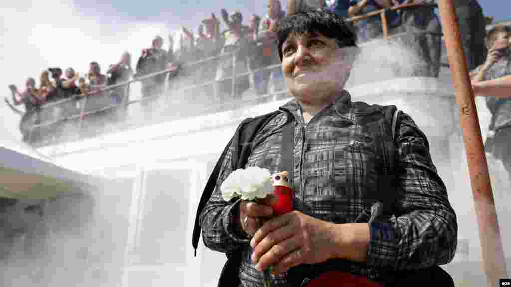 Une femme porte des fleurs et une bougie pour rendre hommage au milieu de terrain camerounais de Dinamo Patrick Claude Ekeng lors d'une cérémonie d'adieu au stade du Dinamo Bucarest, en Roumanie, le 13 mai 2016. epa/ROBERT GHEMENT