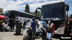 FILE - Passengers board buses traveling to Zimbabwe, amid the spread of the SARS-CoV-2 Omicron variant in Johannesburg, South Africa, Dec. 14, 2021. 