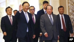 Chinese State Councilor Yang Jiechi, front left, waves as he arrives with Cambodian Deputy Prime Minister and Foreign Minister Hor Namhong, front right, for their meeting at Diaoyutai State Guesthouse in Beijing Thursday, Feb. 4, 2016. (How Hwee Young/Pool Photo via AP)