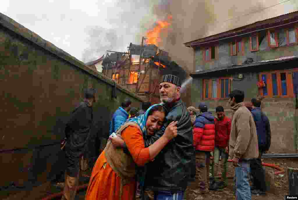 A woman is consoled by her relative as she cries after seeing her house getting burned during a fire in a residential area in Srinagar, India.