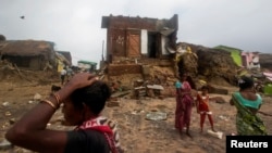Cư dân làng chài đứng trước nhà cửa bị hư hại vì bão tại bang Odisha ở miền đông Ấn Độ, ngày 14/10/2013.