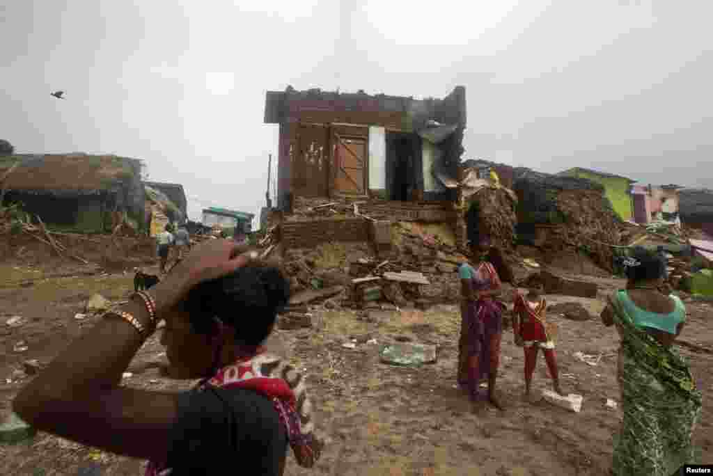 Fisherwomen and a girl stand in front of damaged house after Cyclone Phailin hit Puri in the eastern Indian state of Odisha, Oct. 14, 2013.