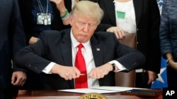 FILE - President Donald Trump takes the cap off a pen before signing an executive order on immigration during a visit to the Homeland Security Department in Washington, Jan. 25, 2017. Following recent terror attacks in London, Trump has renewed calls for 