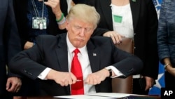 FILE - President Donald Trump takes the cap off a pen before signing an executive order on immigration during a visit to the Homeland Security Department in Washington, Jan. 25, 2017. Following recent terror attacks in London, Trump has renewed calls for a travel ban.