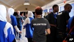 FILE - In this July 17, 2017, photo, the Afghanistan team, left, walks past two of the team members from Burundi, at right in black shirts, during the FIRST Global Robotics Challenge in Washington. 