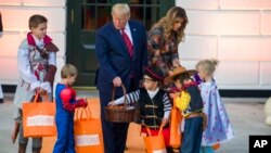 President Donald Trump and first lady Melania Trump give candy to children during a Halloween trick-or-treat event on the South Lawn of the White House which is decorated for Halloween, Monday, Oct. 28, 2019, in Washington. (AP Photo/Alex Brandon)