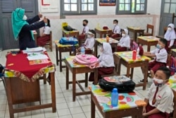 Para murid mengenakan masker selama mengikuti pembelajaran tatap muka (PTM) di ruang kelas mereka, pada hari pertama dibukanya kembali sekolah di tengah pandemi COVID-19, 30 Agustus 2021.