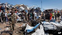 Somali soldiers walk through the wreckage after a car bomb that targeted a police station in the Waberi neighborhood, where President Hassan Sheikh Mohamud was visiting a university, in the capital Mogadishu, Somalia Saturday, Nov. 26, 2016.