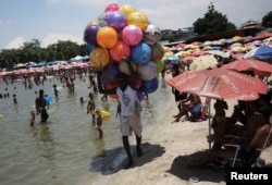 A vendor walks past people relaxing at an artificial pond known as piscinao, or big pool, in the northern suburbs of Rio de Janeiro, Brazil, Jan. 7, 2017.