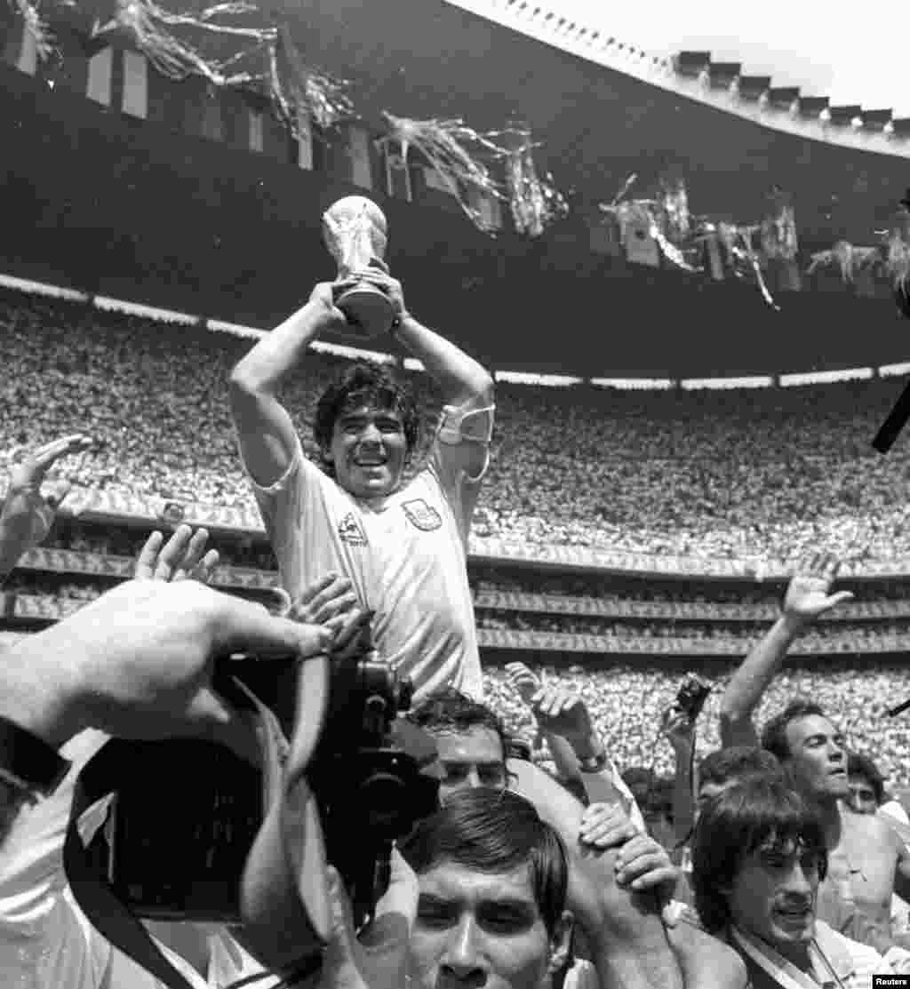 O astro argentino Diego Maradona segura o troféu do Mundial ao ser levado para fora do campo depois que a Argentina derrotou a Alemanha Ocidental por 3 a 2 e ganhou o campeonato mundial de futebol na Cidade do México em 29 de junho de 1986