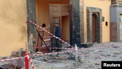 A security guard inspects the damage after a bomb exploded at the gate of the Moroccan embassy in Tripoli, April 13, 2015.