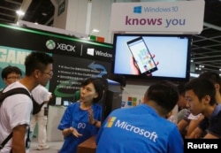 FILE - Promotional staff talk to gamers at the Microsoft Windows 10 booth at Ani-Com & Games Hong Kong in Hong Kong, China.