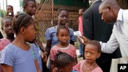 FILE - A health care worker, right, takes the temperatures of school children for signs of the Ebola virus in Conakry, Guinea, Jan. 19, 2015. Guinea begins its countdown to end Ebola, Nov. 17, 2015.