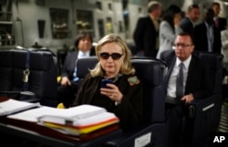 FILE - In this Oct. 18, 2011, file photo, then-Secretary of State Hillary Rodham Clinton checks her Blackberry from a desk inside a C-17 military plane upon her departure from Malta, in the Mediterranean Sea, bound for Tripoli, Libya.