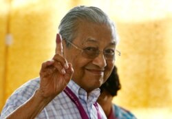 រូប​ឯកសារ៖ លោក Mahathir Mohamad លើក​ម្រាម​ដៃ​ដែល​ប្រឡាក់​ទឹក​ថ្នាំ​ នៅ​ពេល​លោក​បោះឆ្នោត​នៅ​ក្នុង​ការ​បោះឆ្នោត​សកល​មួយ​នៅ​ក្នុង​ក្រុង Alor Setar ប្រទេស​ម៉ាឡេស៊ី កាលពី​ថ្ងៃទី៩ ខែឧសភា ឆ្នាំ២០១៨។