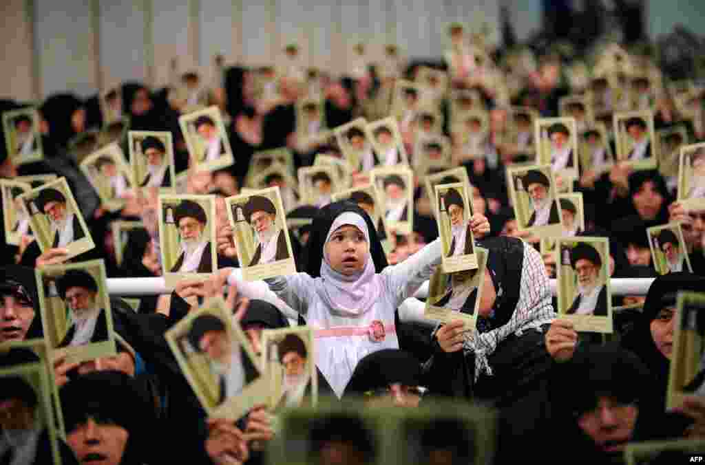 Picture released by the official website of Iranian Supreme Leader Ayatollah Ali Khamenei shows Iranian women and a girl holding up portraits of him during a meeting in Tehran.