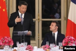 Chinese President Xi Jinping speaks next to French President Emmanuel Macron during a state dinner at the Elysee Palace in Paris, France March 25, 2019. REUTERS.