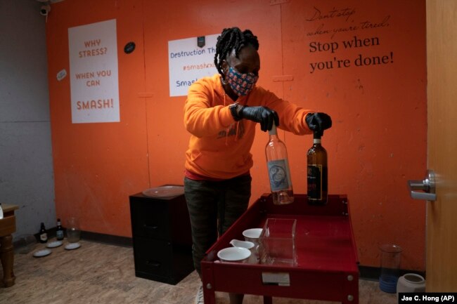 Yashica Budde, a therapist and owner of Smash RX LLC, sets up a rage room with wine bottles for people to break in Westlake Village, California, Feb. 5, 2021. (AP Photo/Jae C. Hong)