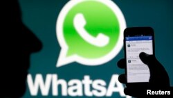 FILE - A WhatsApp logo is seen behind a smartphone, Feb. 20, 2014. Authorities in Afghanistan are temporarily blocking WhatsApp and Telegram social media services in the country.