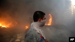 A Hezbollah civil defense worker walks past a burned car at a car bomb in the southern suburb of Beirut, Lebanon, Thursday, Aug. 15, 2013. 