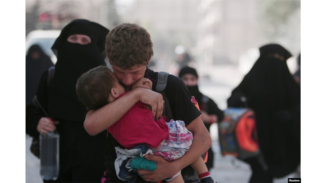 A civilian carries a child as he walks with others after they were evacuated by the Syria Democratic Forces (SDF) fighters from an Islamic State-controlled neighborhood of Manbij, in Aleppo Governorate, Syria, Aug. 12, 2016. The SDF has said Islamic State was using civilians as human shields.