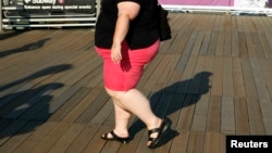 FILE - A woman walks along a boardwalk in New York. Lifestyle and lack of access to healthcare have been among the factors attributed to a rise in the mortality rate of white women in the United States.