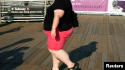 FILE - A woman walks along a boardwalk in New York. The lead author of a new medical study says the severely obese can expect to die 10 years prematurely.