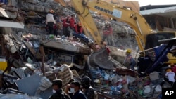 Rescue workers recover a body from the rubble as a bulldozer removes the debris of a collapsed building felled by a 7.8-magnitude earthquake, in Manta, Ecuador, April 19, 2016. 