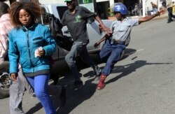 FILE: A riot police man kicks out at a man during protests in Harare, Friday, Aug. 16, 2019. The main opposition Movement For Democratic Change party is holding protests over deteriorating economic conditions in the country.