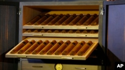 FILE - Cigars lay inside of a humidor made with panels of 24-karat gold-plated tobacco leaves in Havana, Cuba, Feb. 29, 2016. 