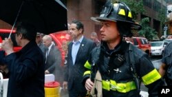 New York Gov. Andrew Cuomo, center, and first responder personnel walk near the scene where a helicopter was reported to have crash landed on top of a building in midtown Manhatta, June 10, 2019, in New York.