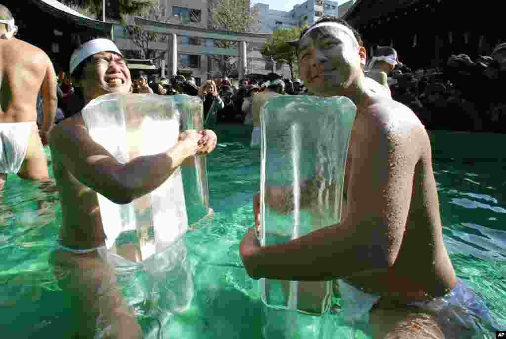 Japanese physical fitness enthusiasts hold blocks of ice while standing in cold water at Teppozu Inari Shinto shrine during a winter ritual to keep themselves fit and to display their perseverance in Tokyo.&nbsp;