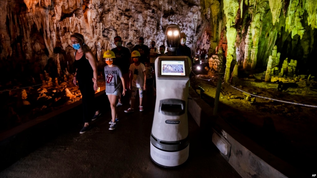 Persephone guides the visitors inside Alistrati cave, about 135 kilometers northeast of Thessaloniki, Greece, Monday, Aug. 2, 2021. (AP Photo/Giannis Papanikos)