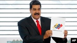 FILE - Venezuela's President Nicolas Maduro holds up the National Electoral Council certificate declaring him the winner of the presidential election, during a ceremony at CNE headquarters in Caracas, Venezuela, May 22, 2018. As a meeting last August in the Oval Office, President Donald Trump turned to his top aides and asked, why can’t the U.S. just simply invade the troubled country?