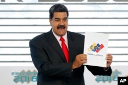 FILE - Venezuela's President Nicolas Maduro holds up the National Electoral Council certificate declaring him the winner of the presidential election, during a ceremony at CNE headquarters in Caracas, Venezuela, May 22, 2018.