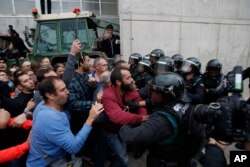 FILE - Civil guards clear people away from the entrance of a sports center, assigned to be a referendum polling station by the Catalan government in Sant Julia de Ramis, near Girona, Spain, Oct. 1, 2017.