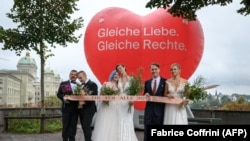 Beberapa pasangan berfoto bersama di ibu kota swiss, Bern, setelah proses referendum yang dilakukan di negara tersebut pada Minggu (26/9) memutuskan untuk mengakui pernikahan pasangan sesama jenis. (Foto: AFP/Fabrice Coffrini)