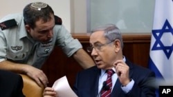 Israel's Prime Minister Benjamin Netanyahu speaks his military secretary Brigadier General Eliezer Toledano, left, during the weekly cabinet meeting at his office, in Jerusalem, Oct. 25, 2015. 