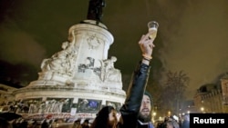 A man holds a glass of champaign on the "Republique" square, a week after a series of deadly attacks in the French capital, in Paris, France, Nov. 20, 2015.