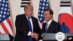 Le président américain Donald Trump, à gauche, et son homologue sud-coréen Moon Jae-In se serrent la main lors d'une conférence de presse conjointe à la Maison présidentielle de Séoul, en Corée du Sud, mardi 7 novembre 2017. 