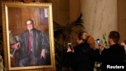 A couple takes photographs of a painting of late U.S. Supreme Court Justice Antonin Scalia in the Great Hall of the Supreme Court in Washington, Feb. 19, 2016.