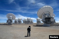 FILE - A member of the media takes pictures of the parabolic antennas of the ALMA (Atacama Large Millimetre/Submillimetre Array) project at the El Llano de Chajnantor in the Atacama desert, some 1,730 km (1,074 miles) north of Santiago and 5,000 meters above sea level, March 12, 2013.