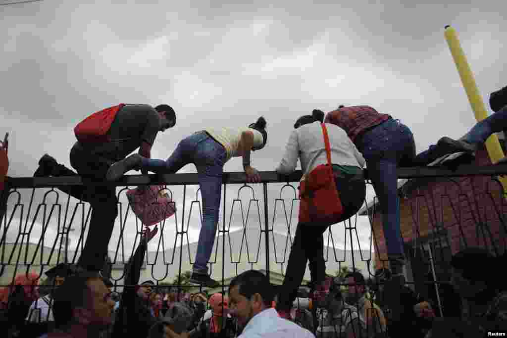 Students climb the fence of the National Pedagogical University during a protest against Sunday's presidential election results in Tegucigalpa November 27, 2013.