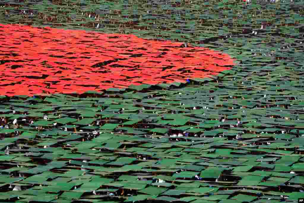 Bangladeshis flip colored cards to form the national flag during Victory Day celebrations in Dhaka.