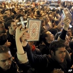 Egyptian Muslims and Christians raise a copy of the Quran and a Cross in Shubra district, Cairo, Egypt, Saturday, Jan.1, 2011 to protest against the terrorist attack on a Coptic Christian church in the northern Egyptian city of Alexandria.